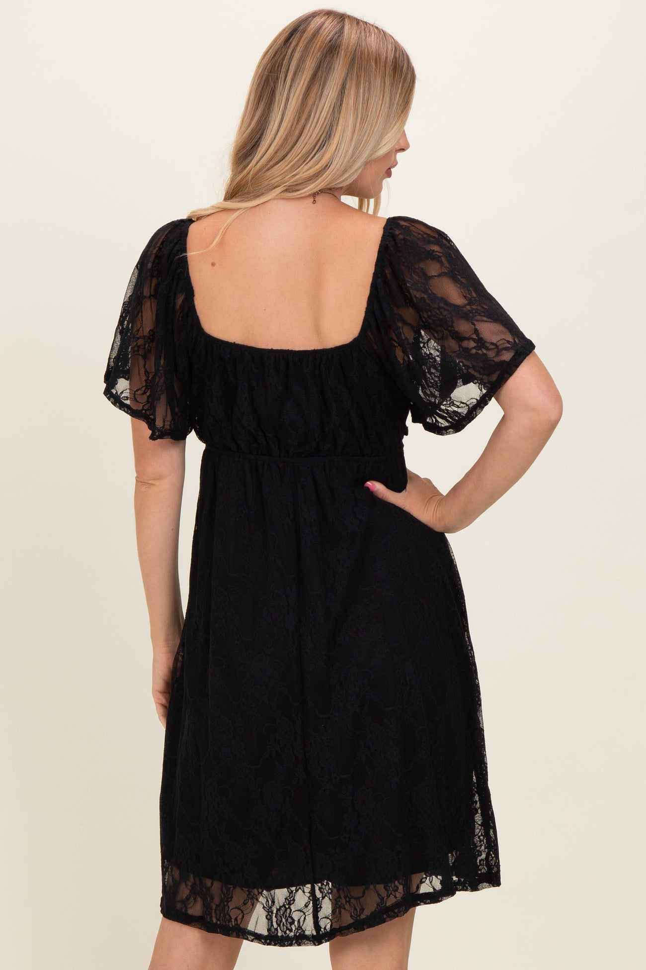 woman wearing a black lace short sleeve dress with a square back and a fitted waist