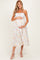 woman wearing a floral maternity dress with spaghetti straps and a baby bump, standing against a neutral background