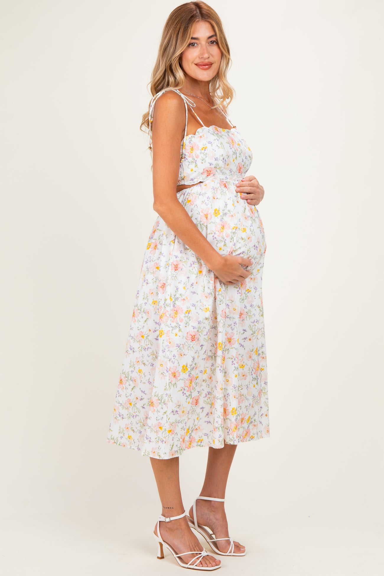 woman wearing a floral maternity sundress and holding her baby bump