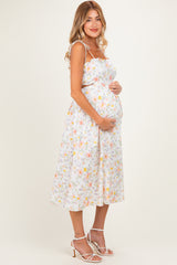 woman wearing a floral maternity sundress and holding her baby bump
