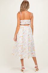 woman wearing a floral maternity two-piece dress with adjustable straps and a flowy skirt, showing her baby bump from the back