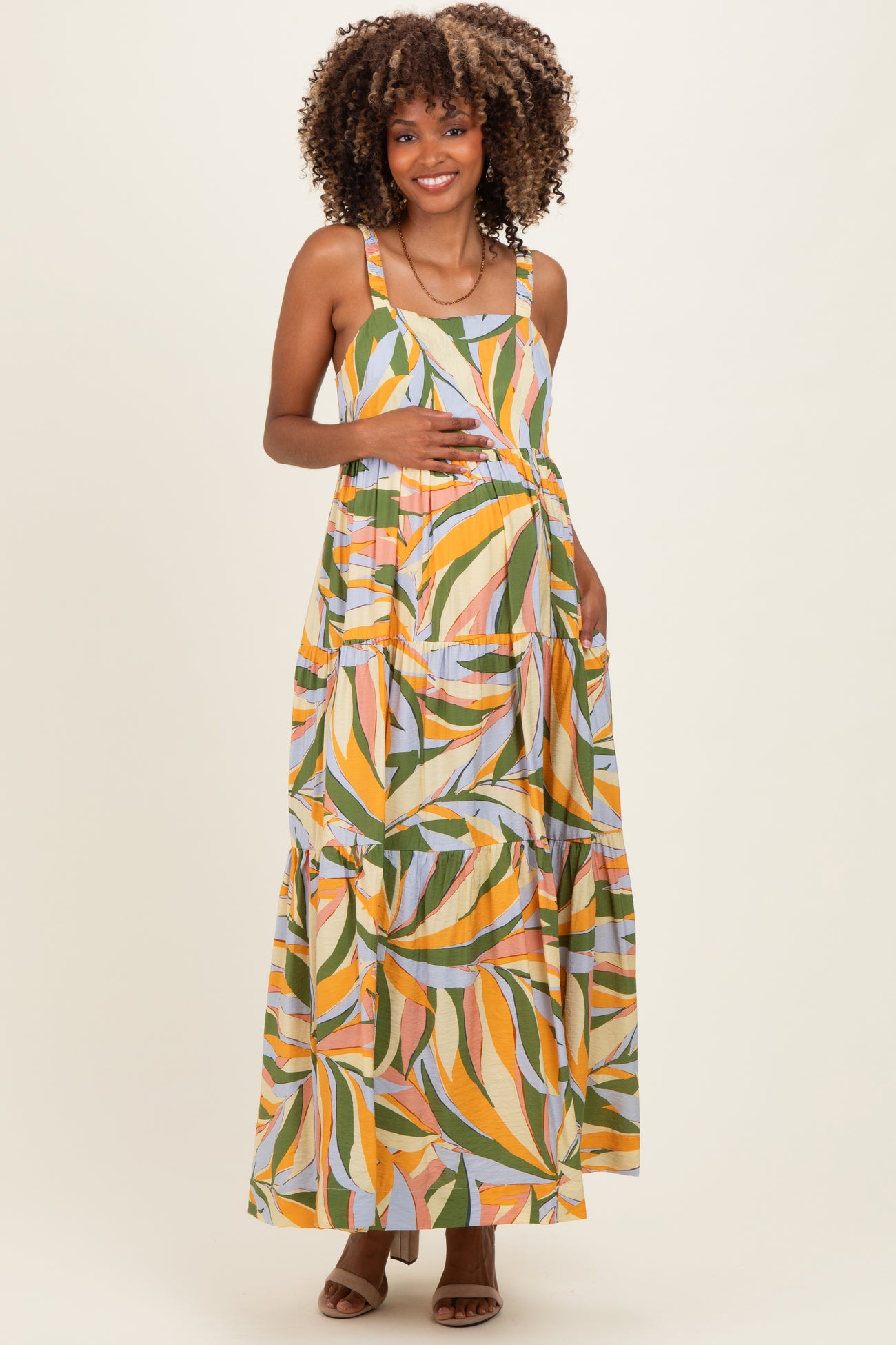 woman wearing a colorfully patterned maternity maxi dress and holding her baby bump