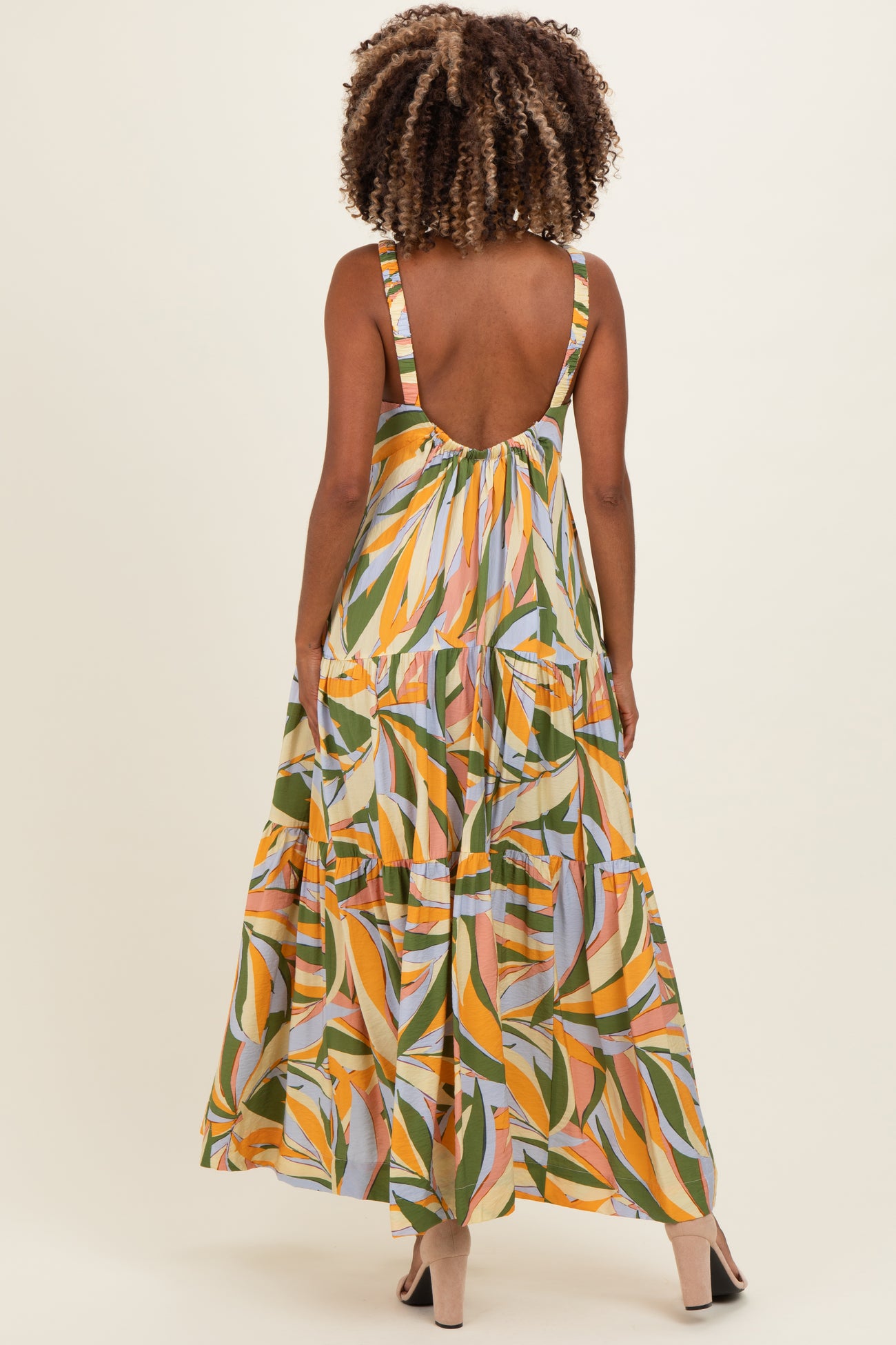 woman wearing a multicolored floral maternity maxi dress with a deep back and tiered skirt