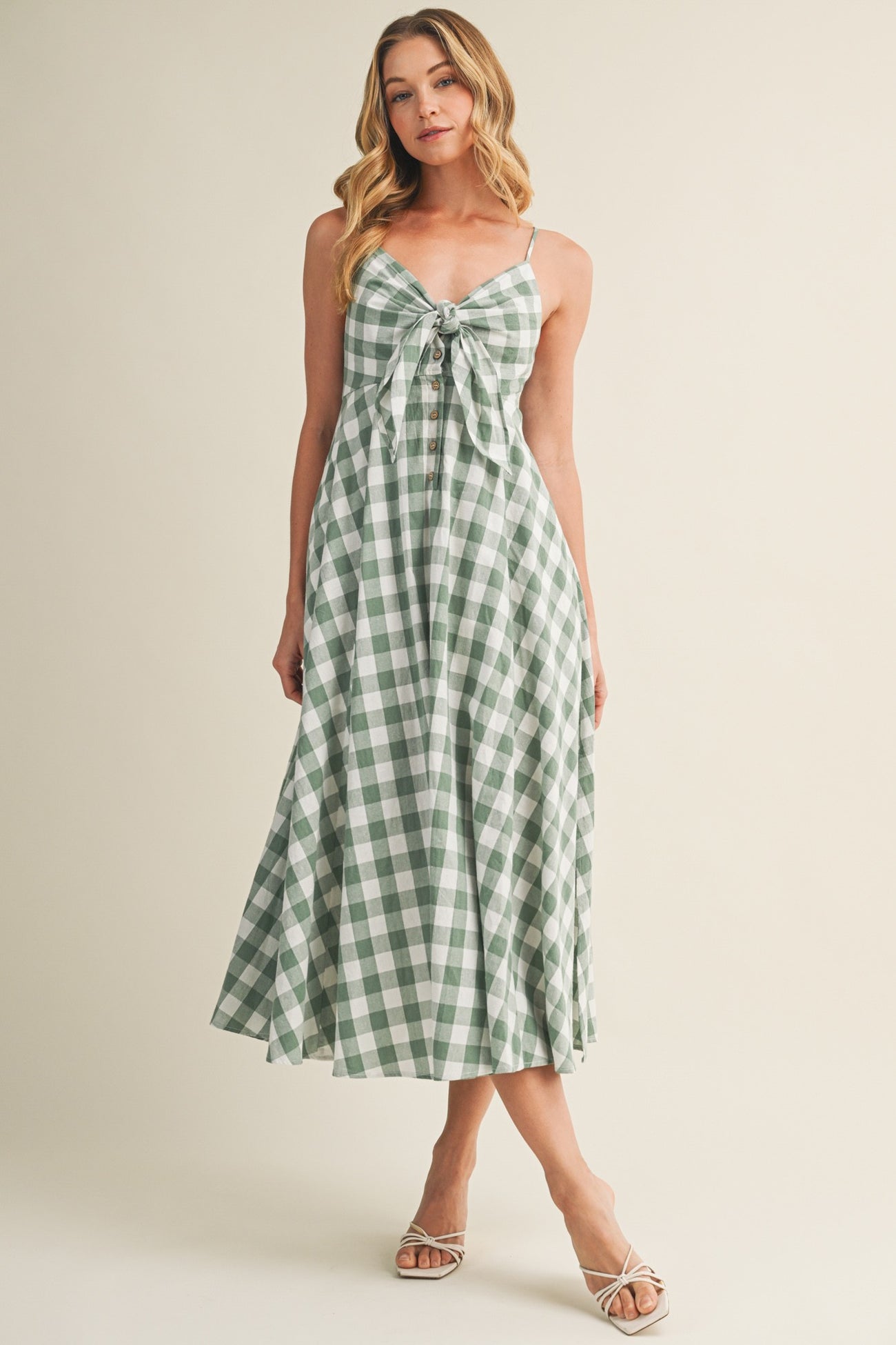 woman wearing a green and white gingham midi dress with a tie front detail and spaghetti straps