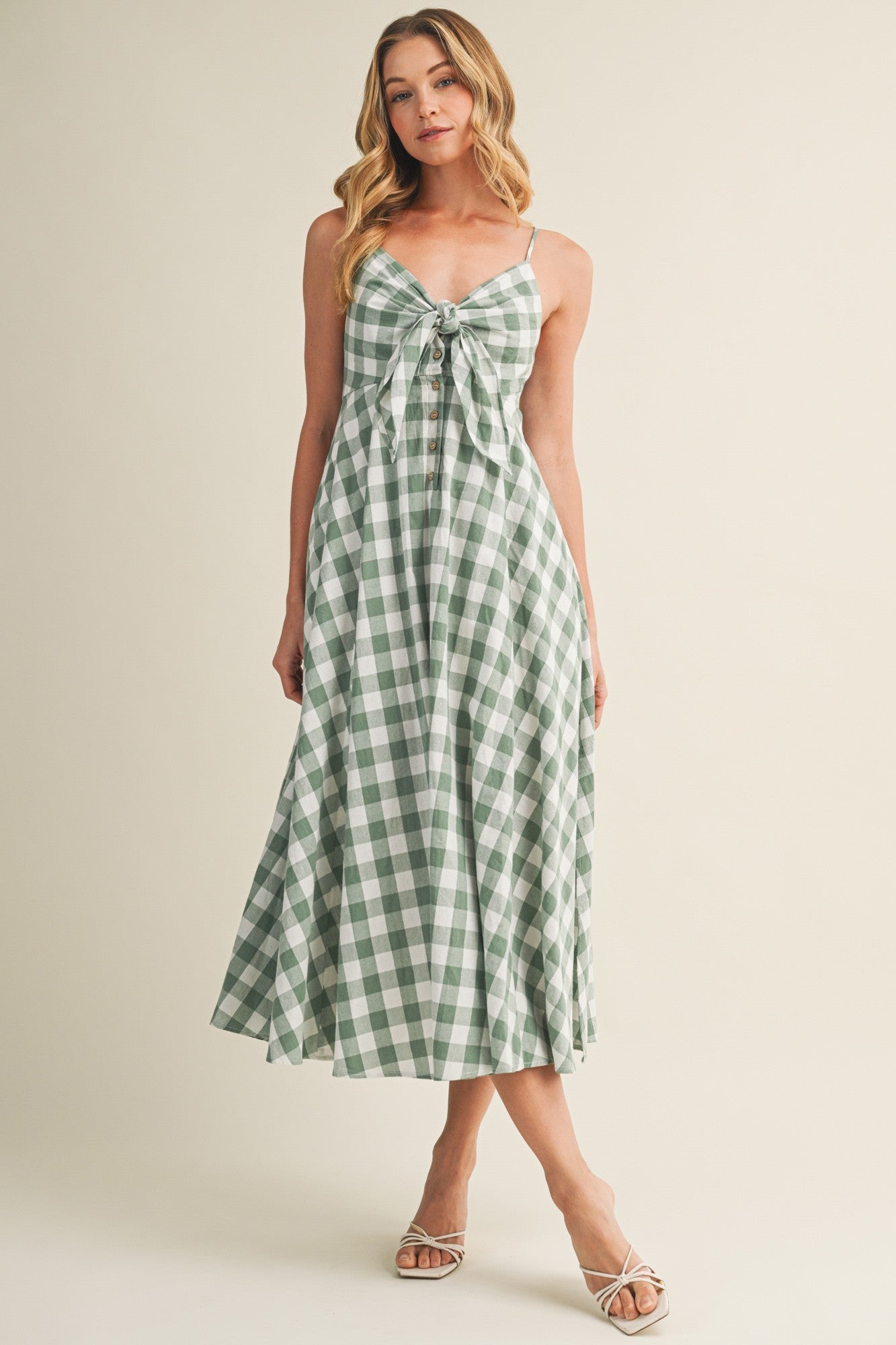 woman wearing a green and white gingham midi dress with a tie front detail and spaghetti straps