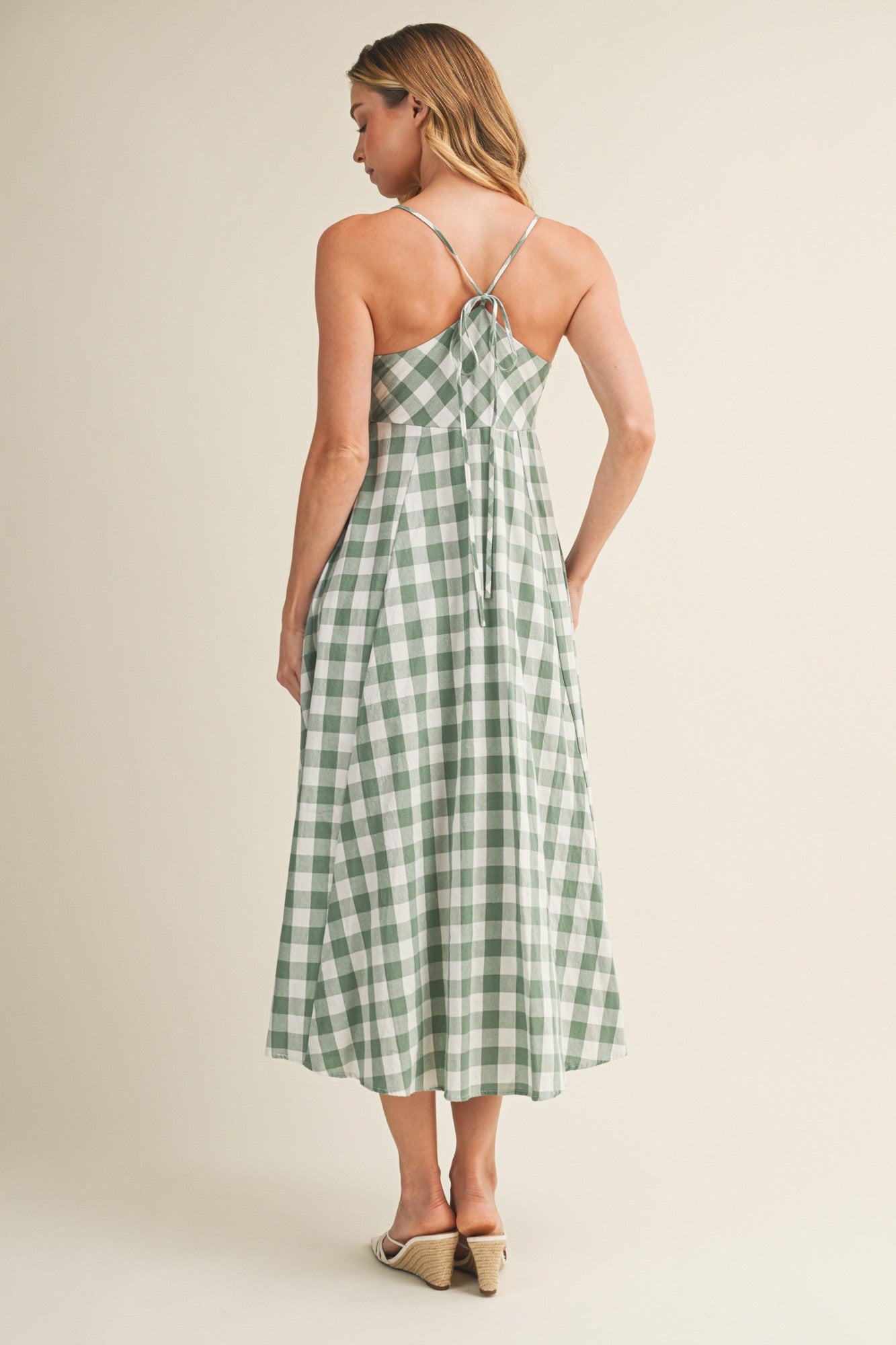 woman wearing a green and white gingham midi dress with a tie-back detail