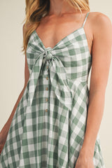 woman wearing a green and white checkered dress with a tied front and button details