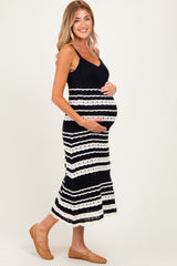 woman wearing a black and white striped maternity dress, holding her baby bump with a smile