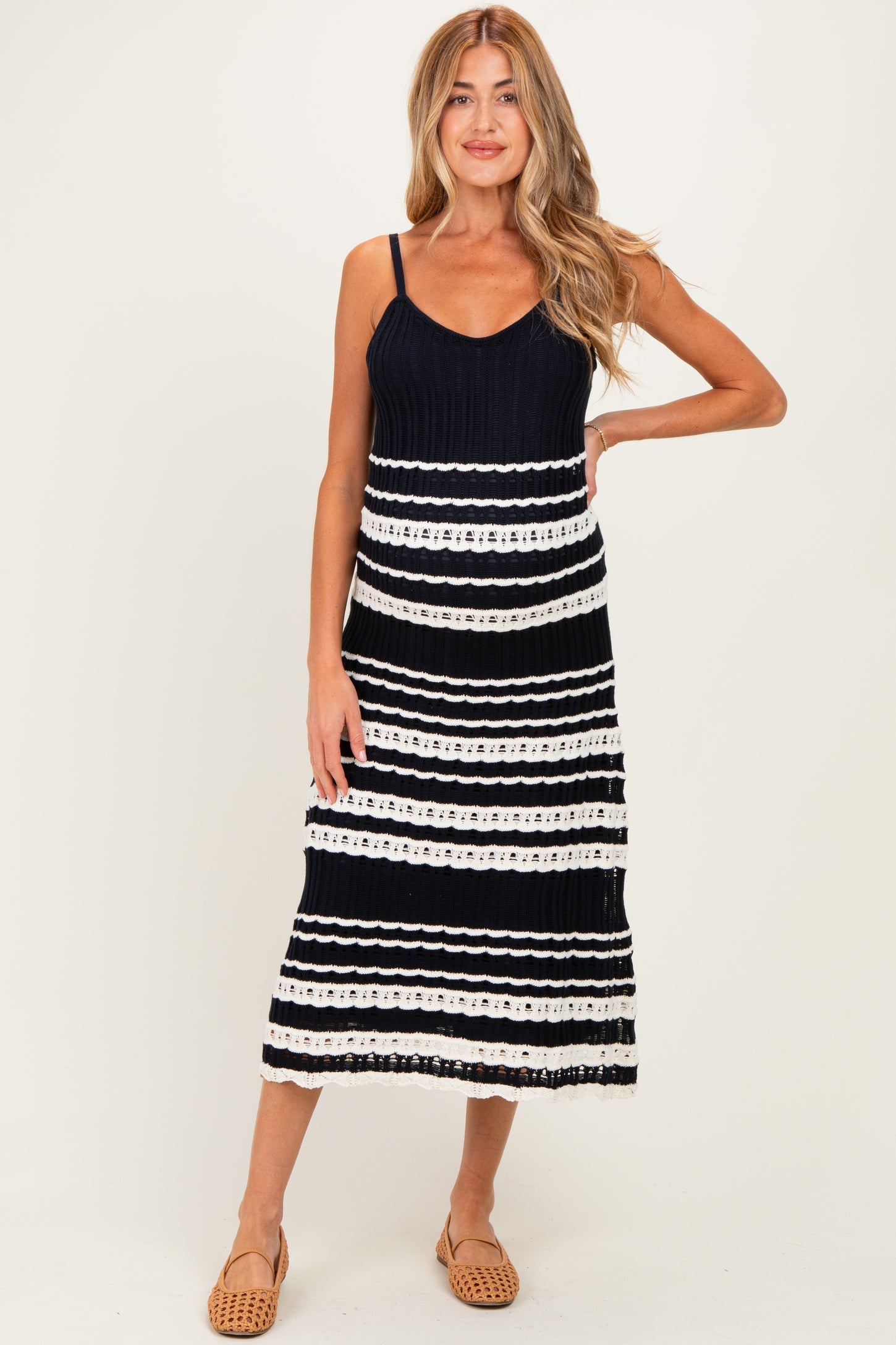 woman wearing a navy blue and white striped maternity dress with adjustable straps and midi length