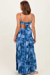 back view of a woman wearing a blue tie-dye maxi dress with a tie detail and tiered skirt