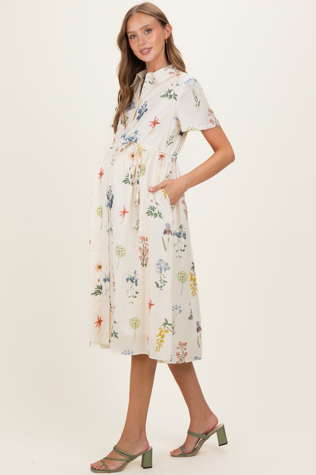 woman wearing a floral short sleeve maternity dress with pockets and a tie waist, showcasing her baby bump