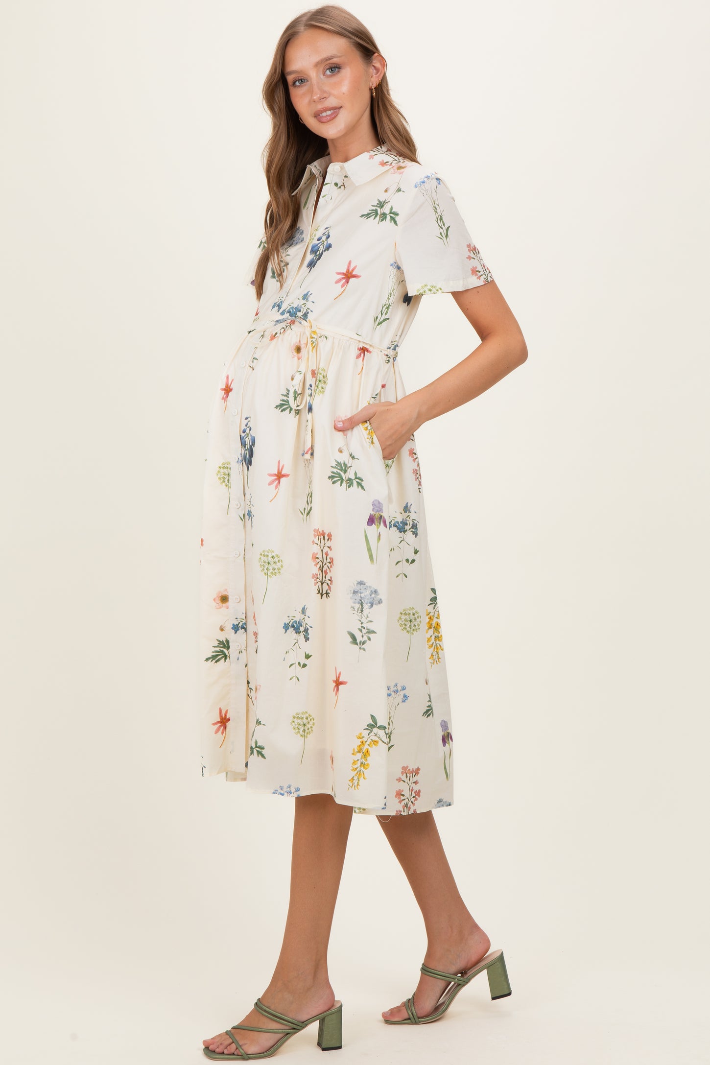 woman wearing a floral short sleeve maternity dress with pockets and a tie waist, showcasing her baby bump
