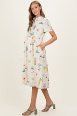 woman wearing a floral short sleeve maternity dress with pockets and a tie waist, showcasing her baby bump