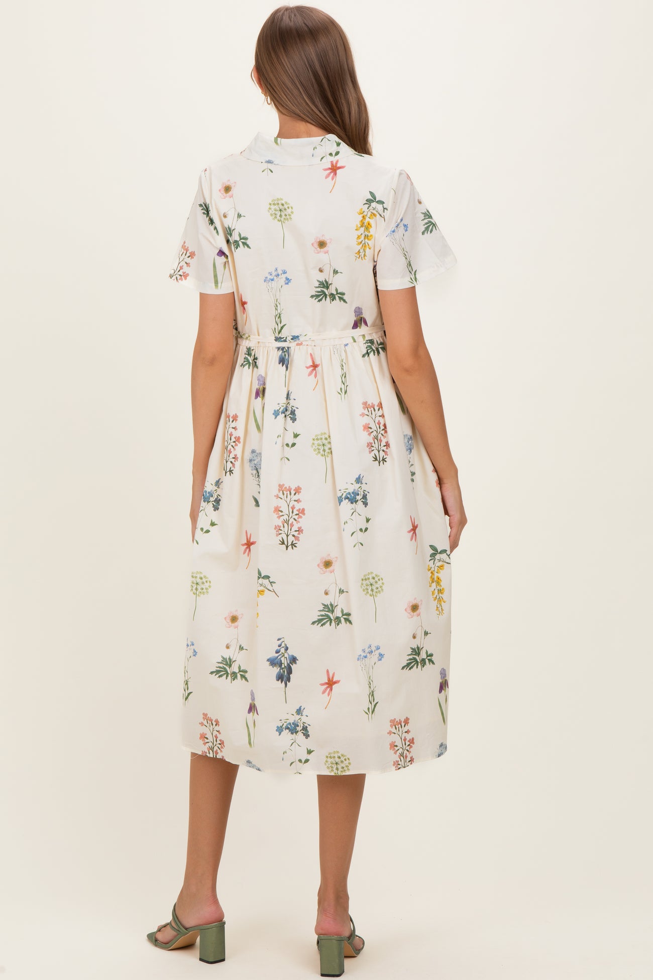 woman wearing a floral print maternity dress with short sleeves and a tiered skirt, showcasing a baby bump
