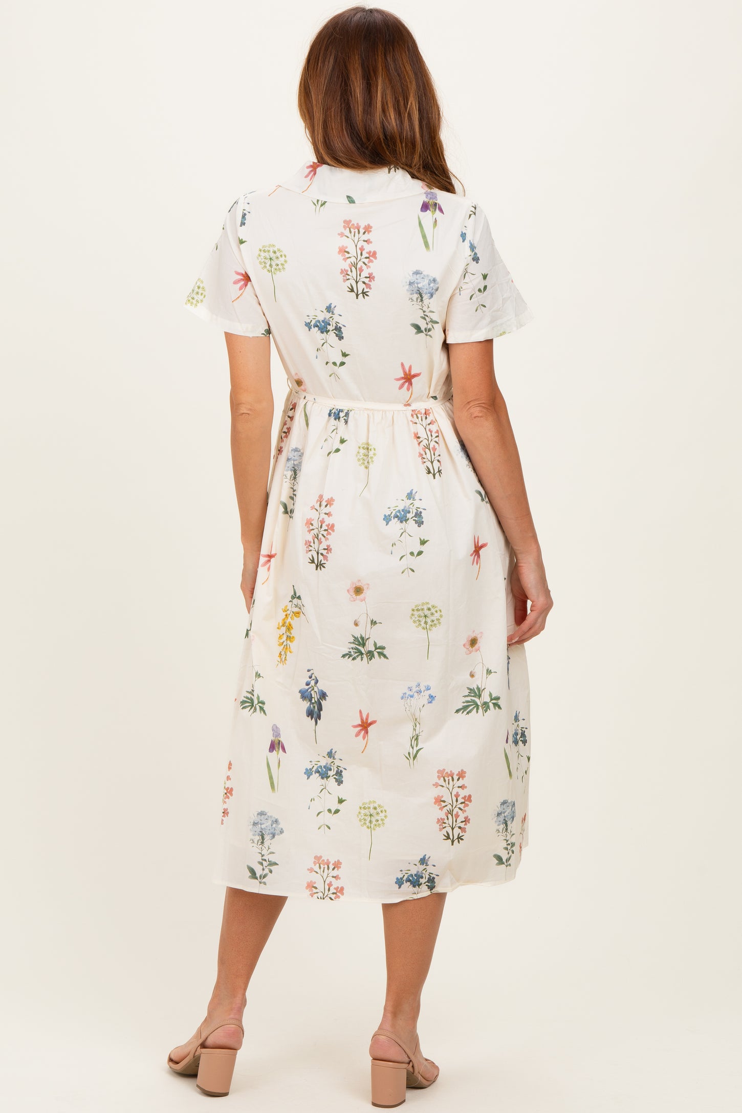 woman wearing a white floral midi dress with short sleeves and a tie waist, shown from the back