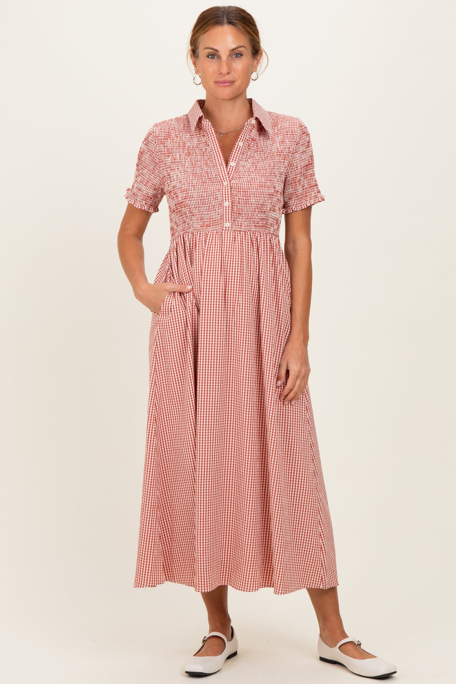 woman wearing a red and white checkered midi dress with short sleeves and a collared neckline, styled with pockets