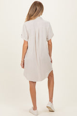 woman wearing a light beige maternity shirt dress with rolled sleeves and a curved hemline