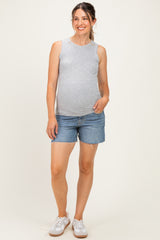 woman wearing a gray tank top and denim shorts with a visible baby bump, styled with white sneakers