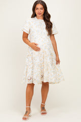 woman wearing a floral print maternity dress with short sleeves and a flared skirt, holding her baby bump