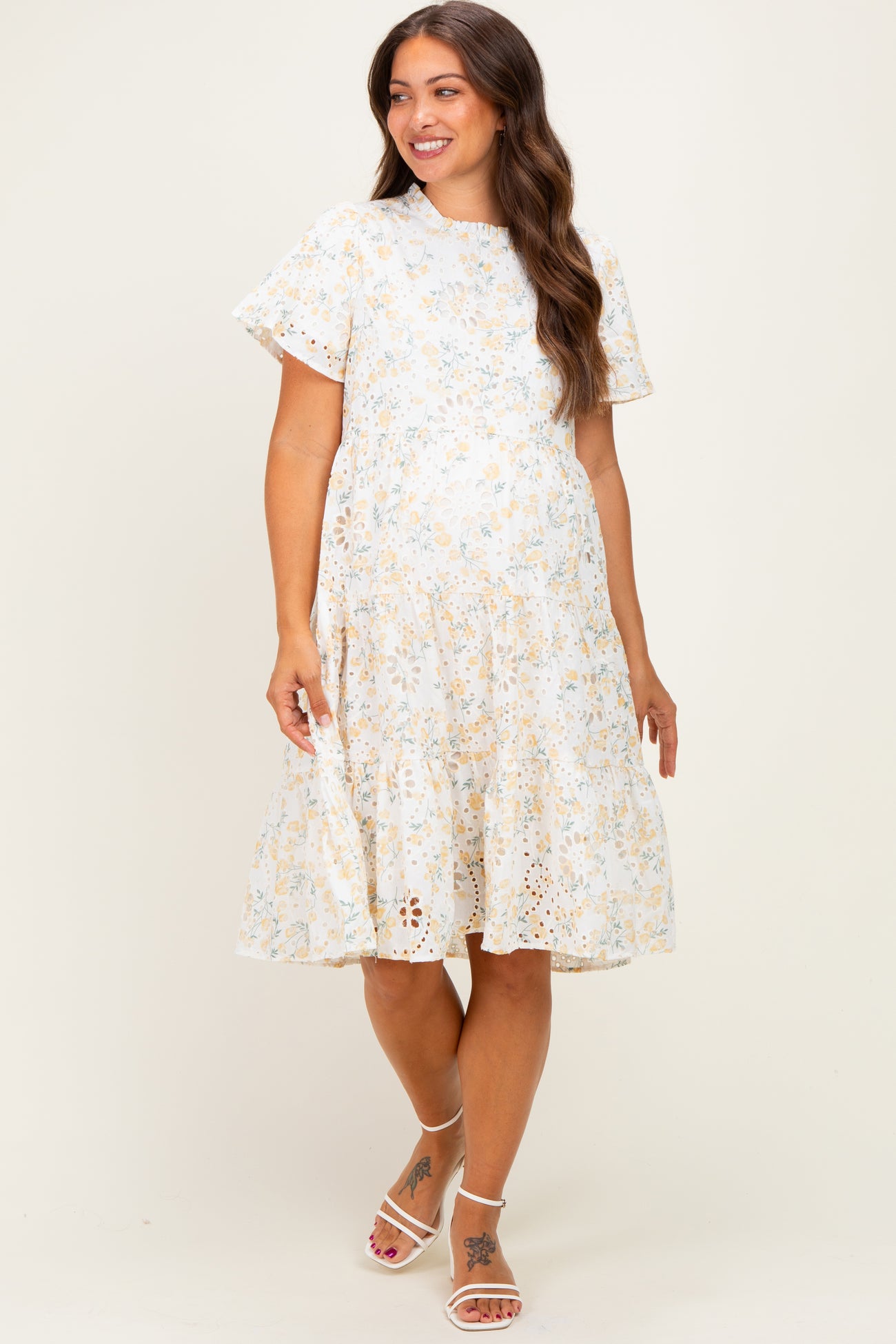 woman wearing a floral print maternity dress with short sleeves and a tiered skirt, showcasing her baby bump