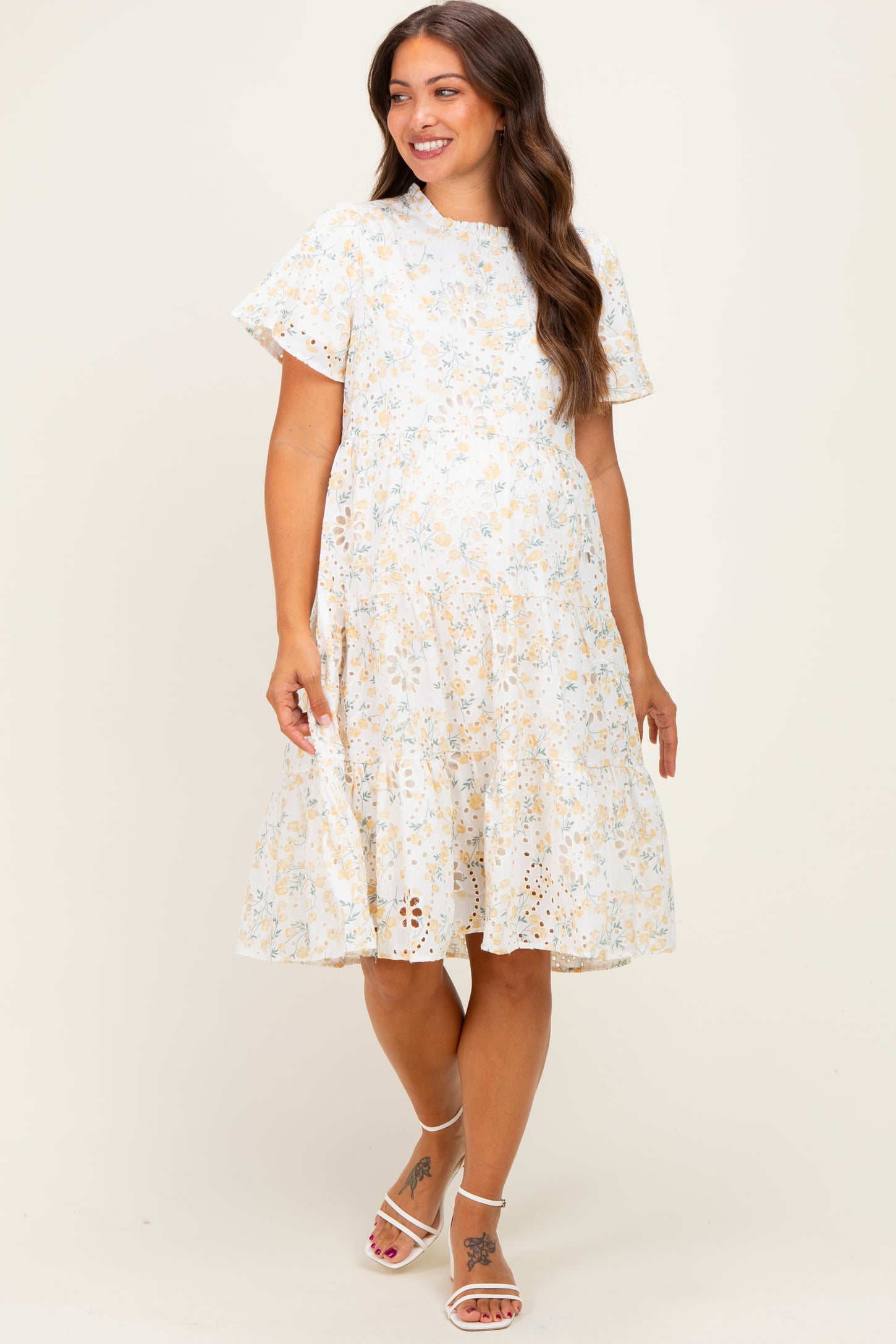 woman wearing a floral print maternity dress with short sleeves and a tiered skirt, showcasing her baby bump