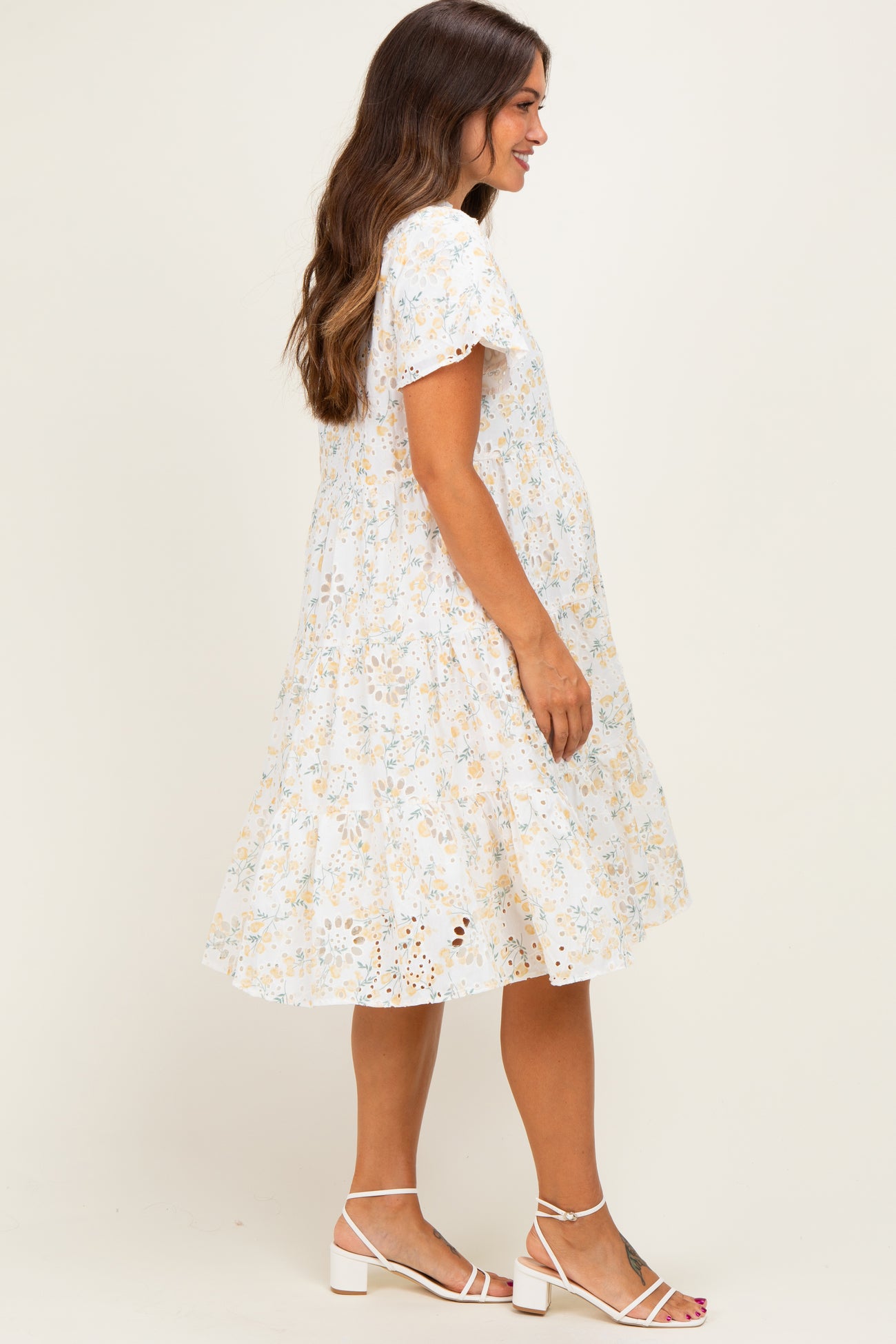 woman wearing a floral print maternity dress with short sleeves and a flowing skirt, showing her baby bump