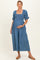 woman wearing a blue denim maternity dress with a smocked bodice and puff sleeves, holding her baby bump