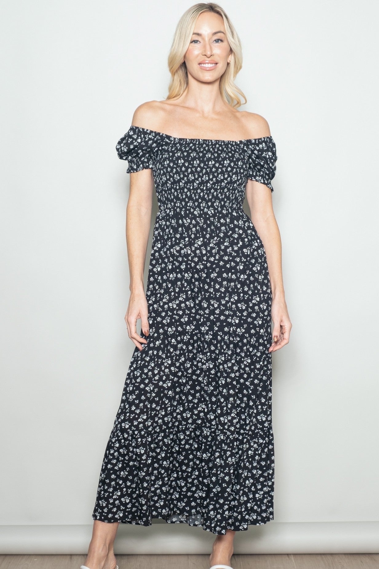 woman wearing a black off-the-shoulder floral maxi dress with puff sleeves and a smocked bodice