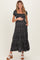 woman wearing a black floral maternity maxi dress, holding her baby bump and smiling