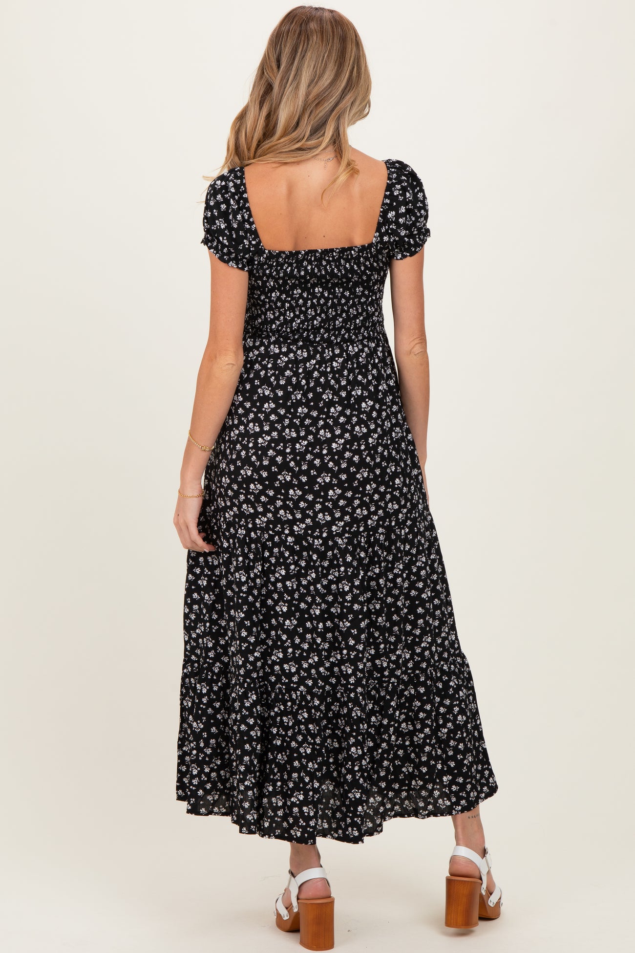 woman wearing a black floral print maternity dress with a square neckline and short puff sleeves