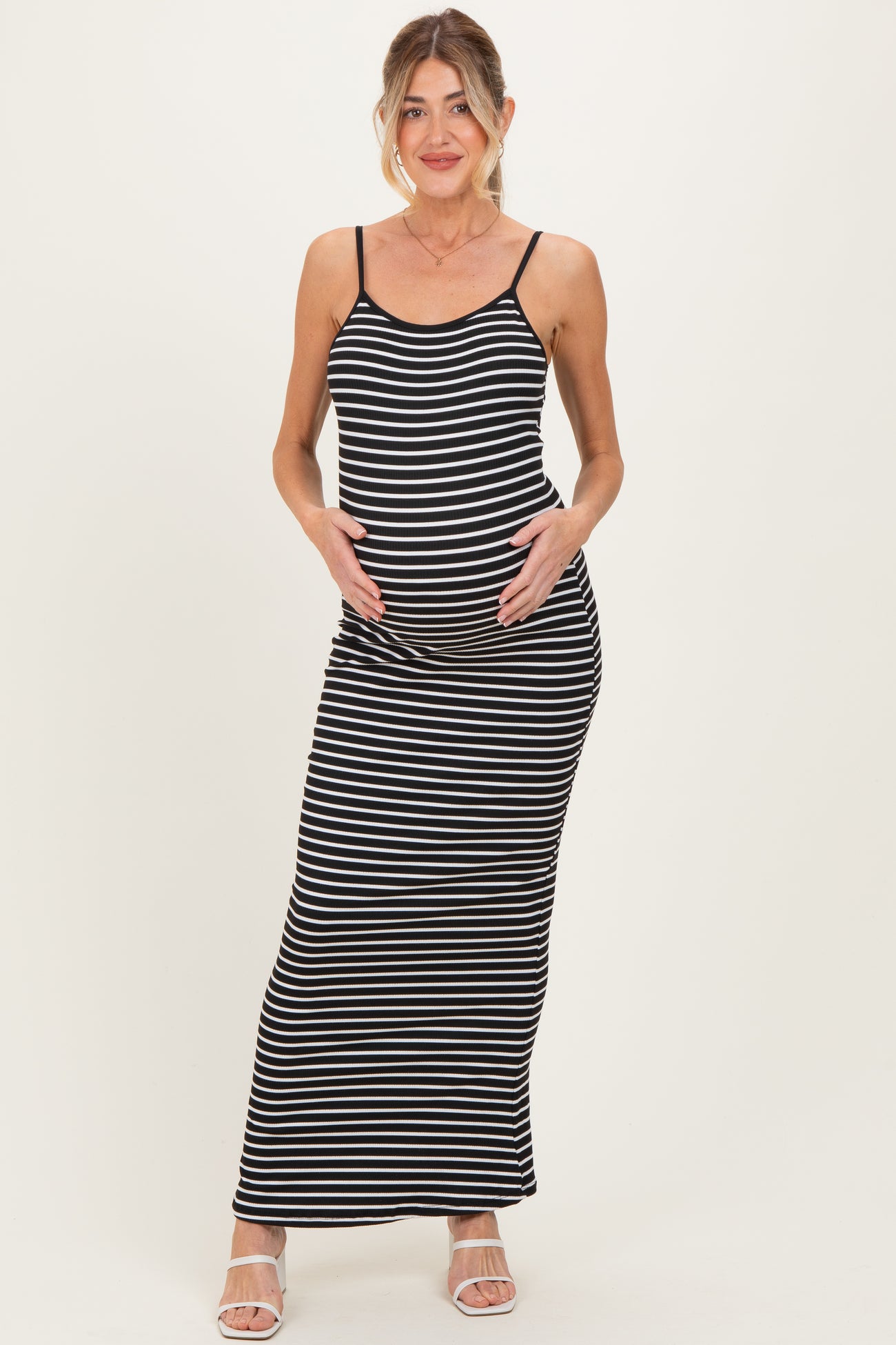 woman wearing a black and white striped maternity maxi dress and holding her baby bump