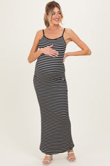 woman wearing a black and white striped maternity maxi dress and gently cradling her baby bump