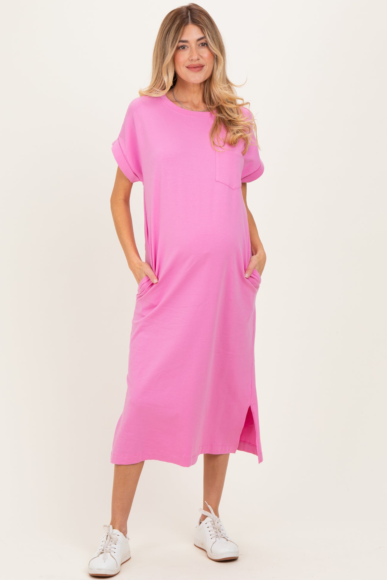 woman wearing a hot pink maternity t-shirt dress with short sleeves and pockets, showcasing her baby bump