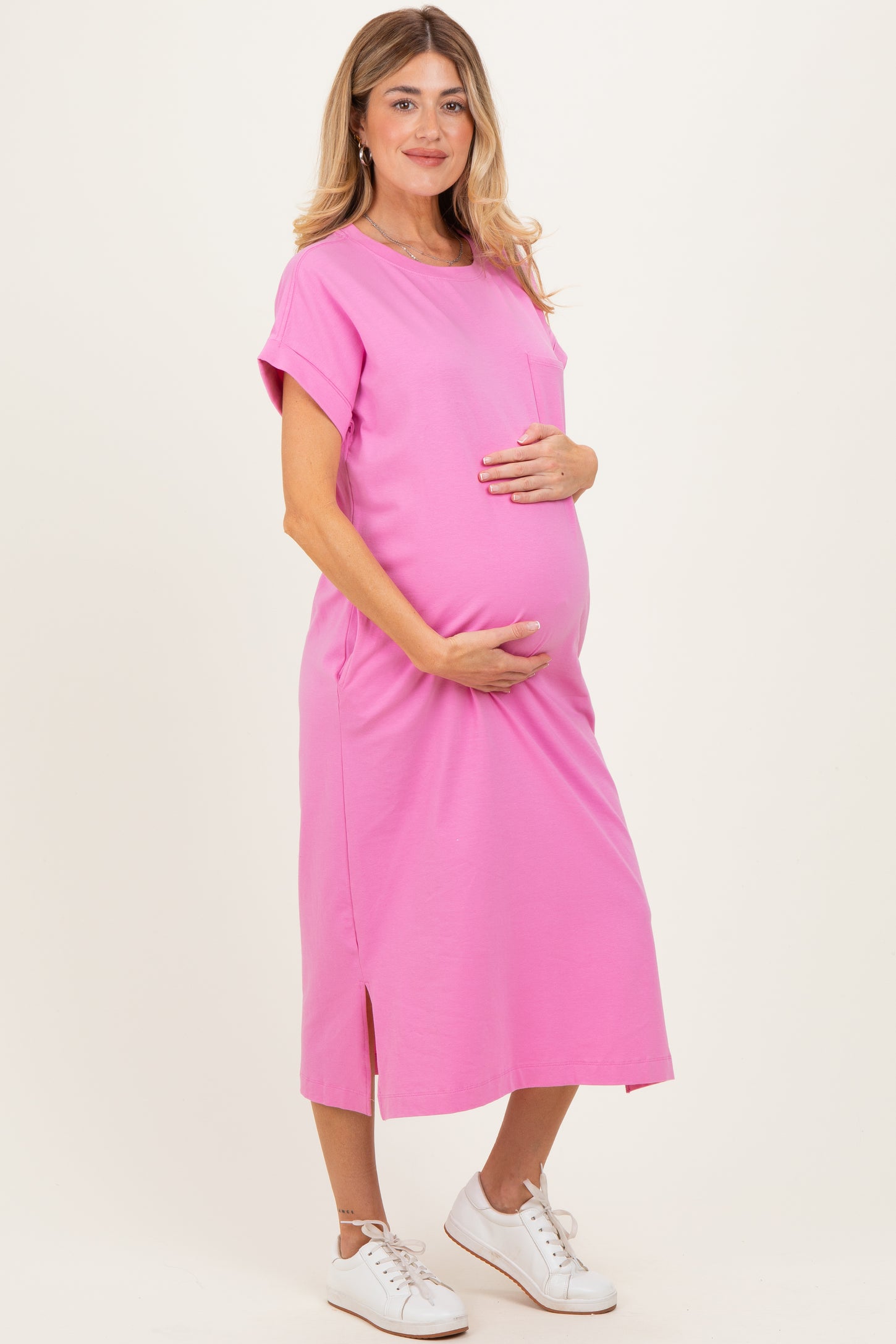 woman wearing a bright pink maternity dress with a side slit, holding her baby bump