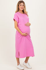 woman wearing a bright pink maternity dress with a side slit, holding her baby bump
