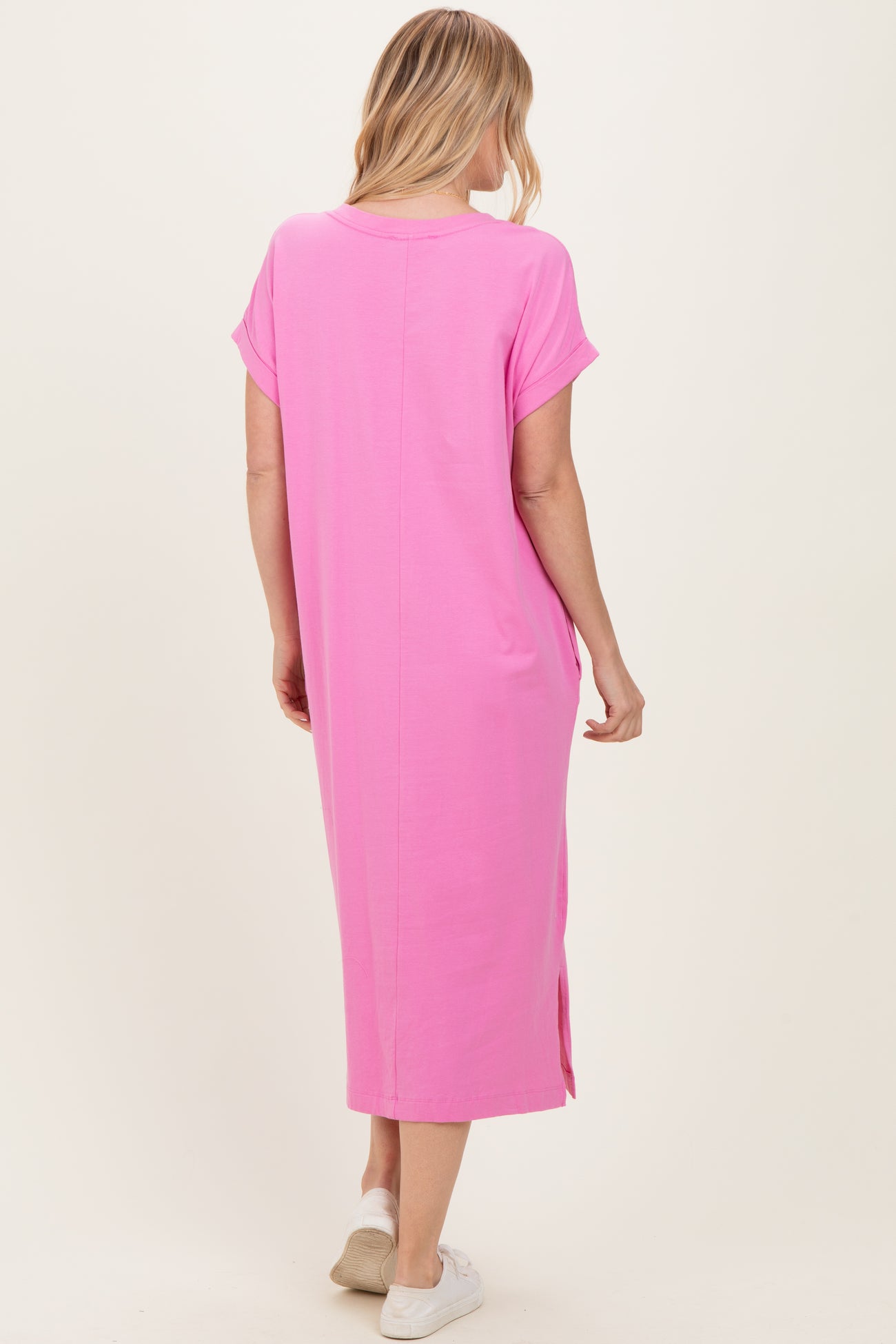 woman wearing a long pink casual dress with short sleeves and side slits, shown from the back