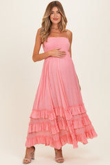 woman wearing a pink maternity maxi dress with ruffles, holding her baby bump
