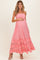 woman wearing a pink maternity maxi dress with ruffles, holding her baby bump