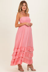 woman wearing a pink maternity maxi dress with ruffles and a smocked bodice, showcasing her baby bump