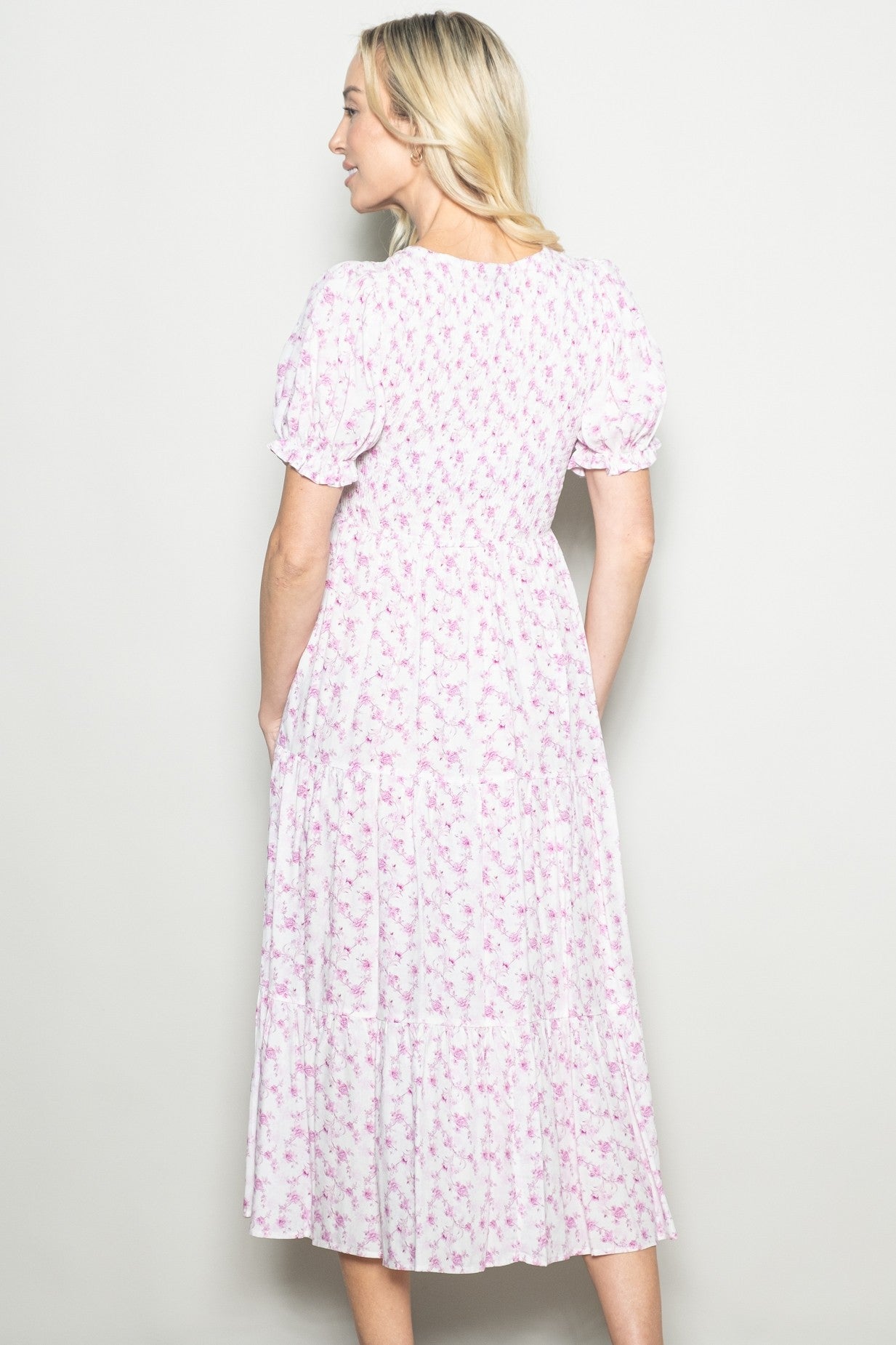 woman wearing a light pink floral midi dress with puff sleeves, shown from the back