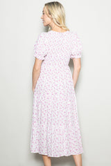 woman wearing a light pink floral midi dress with puff sleeves, shown from the back