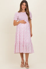 woman wearing a pink floral maternity dress with short sleeves and holding her baby bump