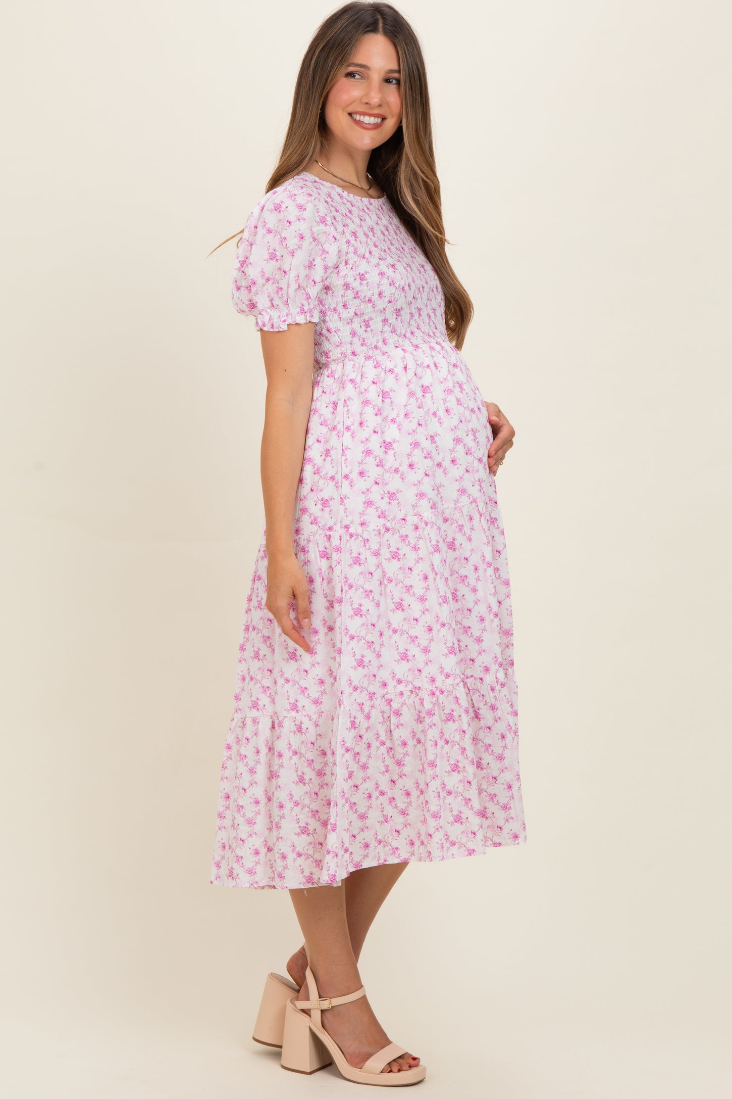 woman wearing a pink floral maternity dress with short puff sleeves and a baby bump visible