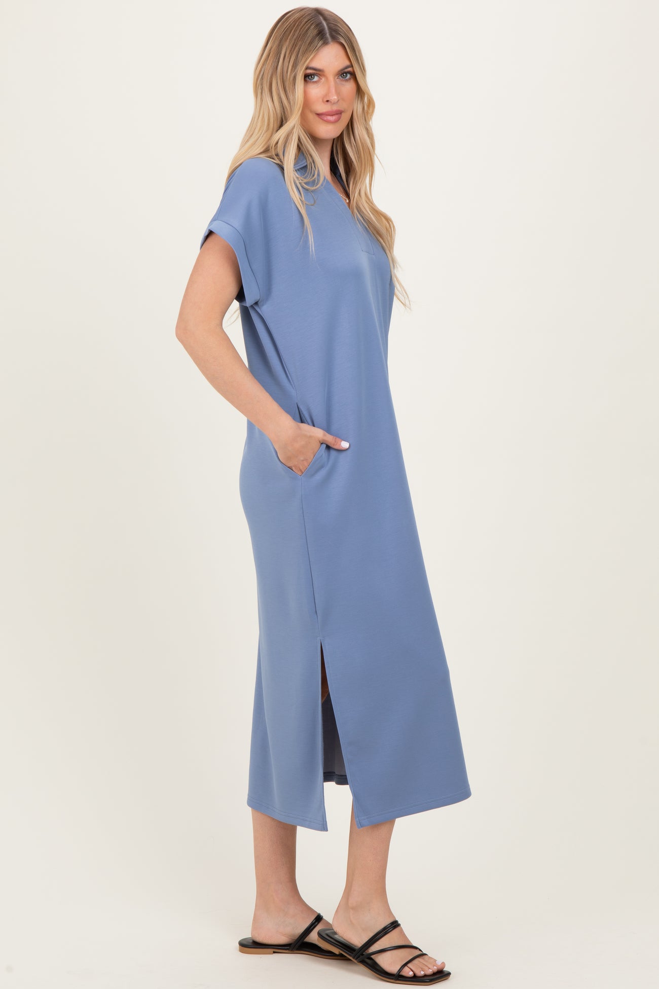 woman wearing a blue short sleeve maxi dress with side pockets and a slit, paired with black sandals
