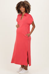 woman wearing a coral maternity maxi dress with pockets, standing and holding her baby bump