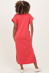 woman wearing a coral maternity maxi dress with short sleeves and side slits, showing her back and hair texture