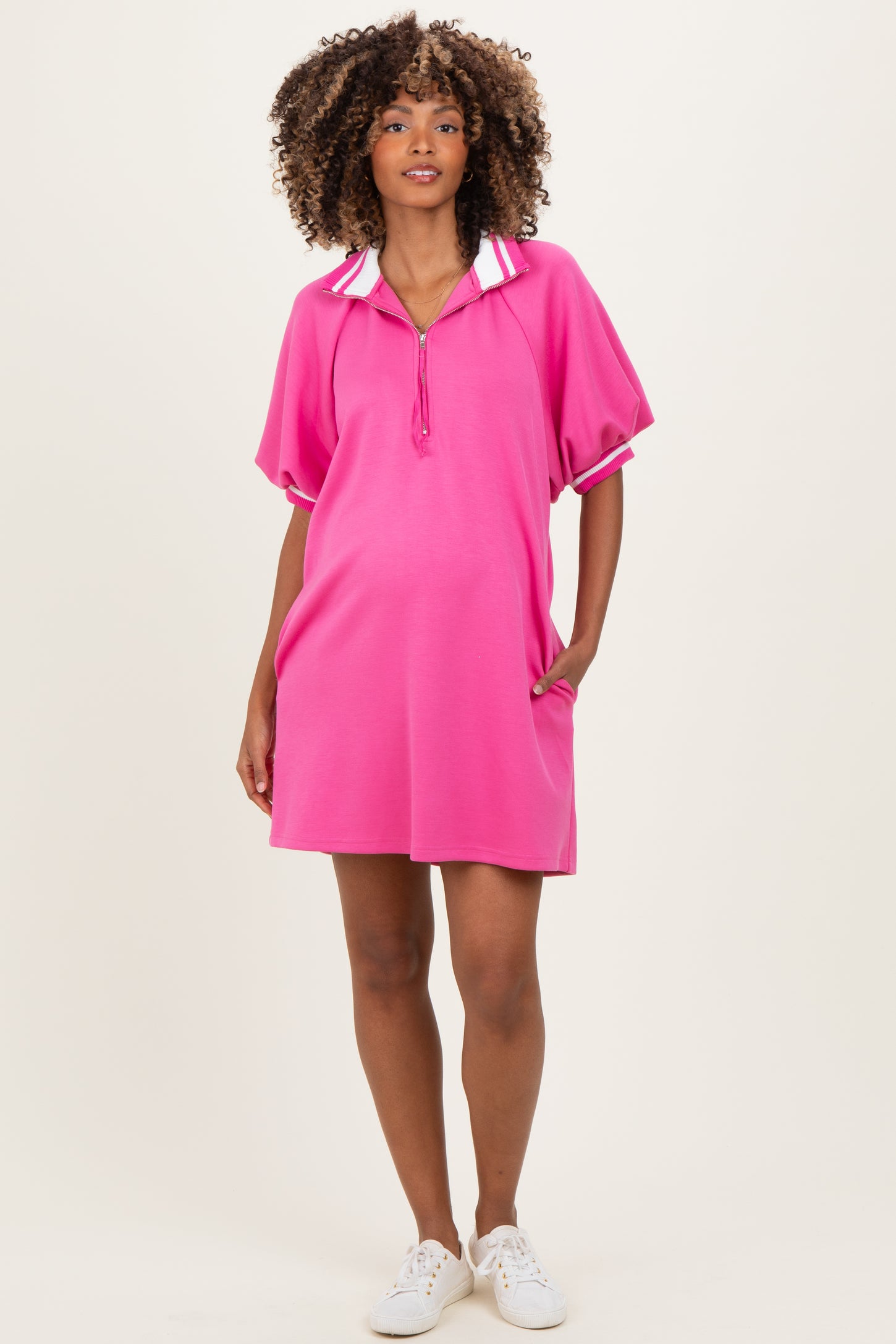 woman wearing a bright pink maternity polo dress with a collar and loose fit, showing her baby bump
