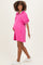 woman wearing a bright pink maternity dress with a polo collar and puff sleeves, showing her baby bump