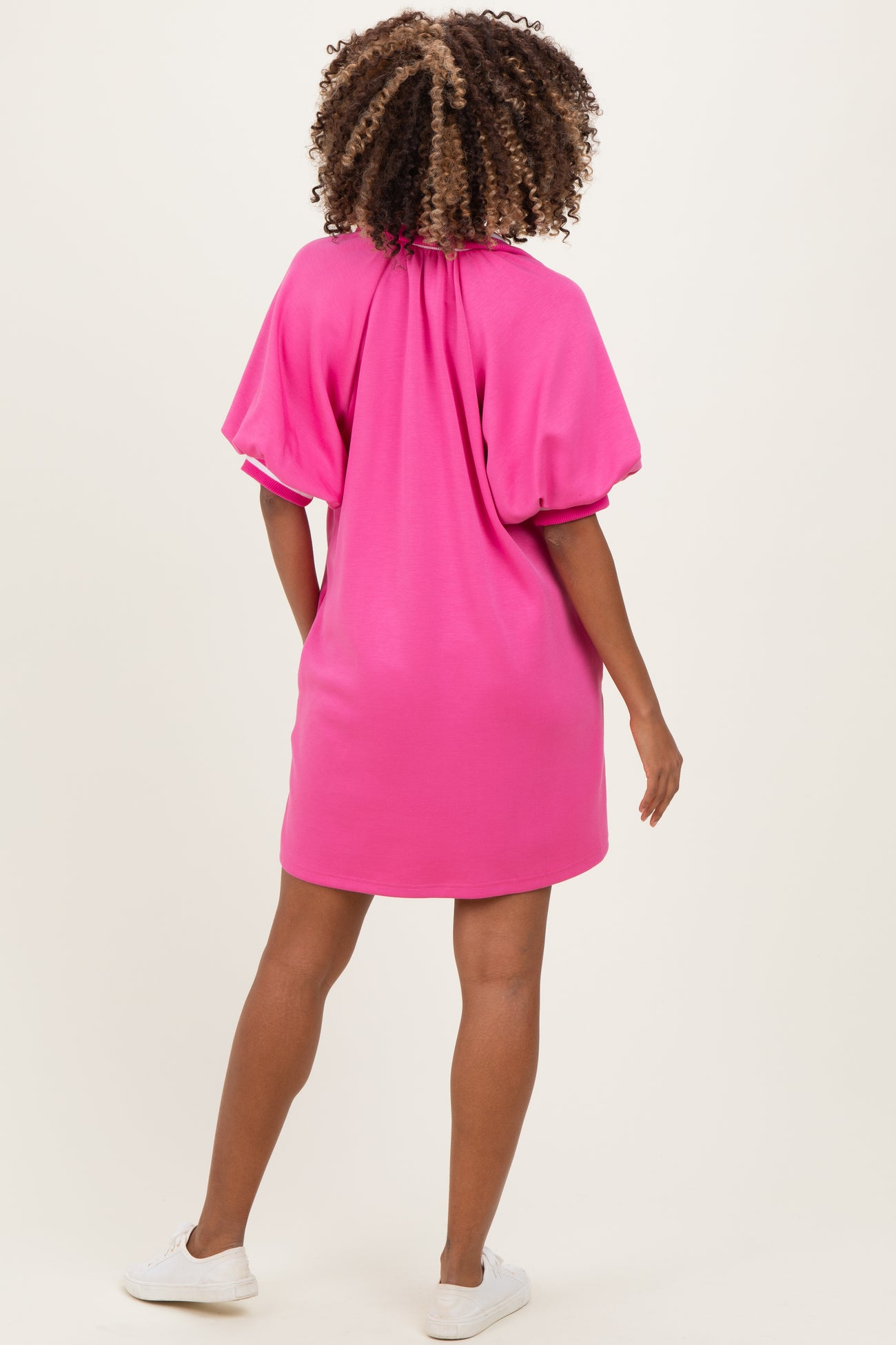 woman wearing a pink maternity dress with puff sleeves and a gathered neckline