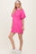 woman wearing a bright pink short sleeve polo dress with a zip collar and white detailing, standing with a headband and white sneakers